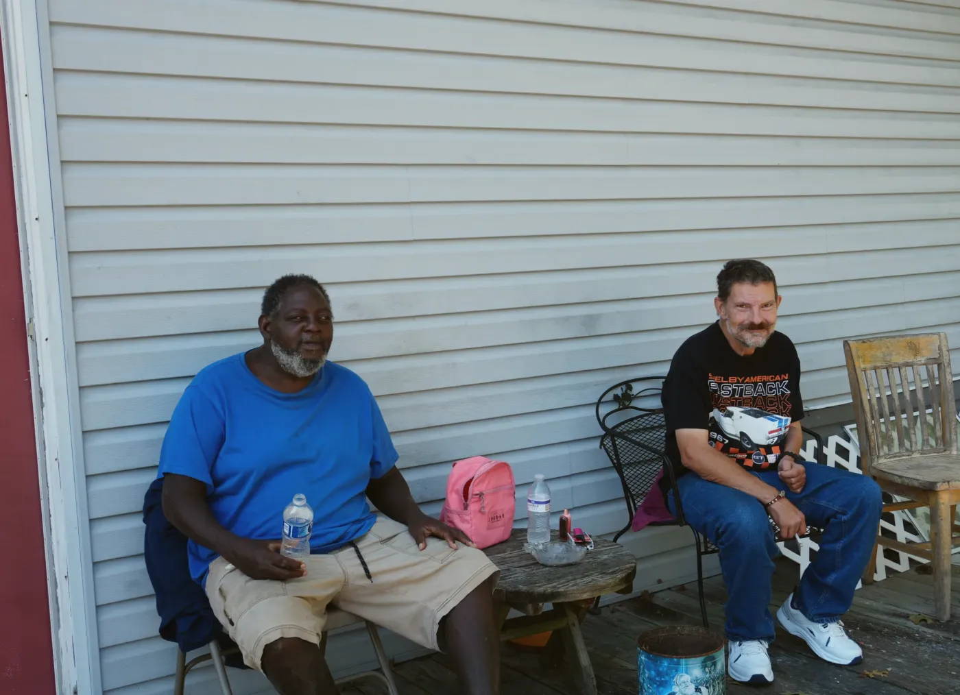 Two men sitting and talking on a porch in the afternoon.