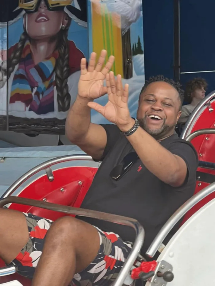 A man waving and laughing on a fairground ride.