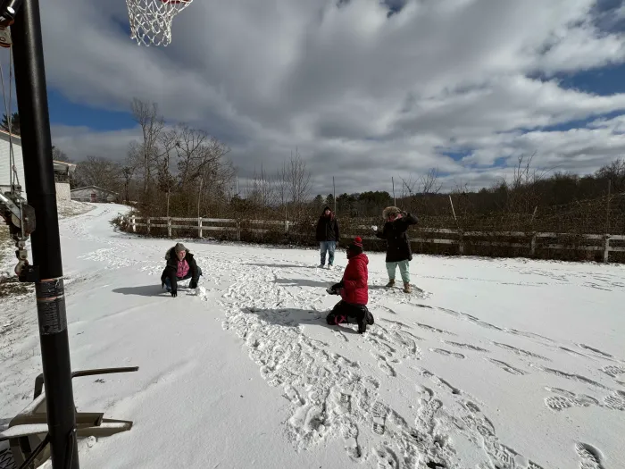 People playing in a snowy field behind the houses.